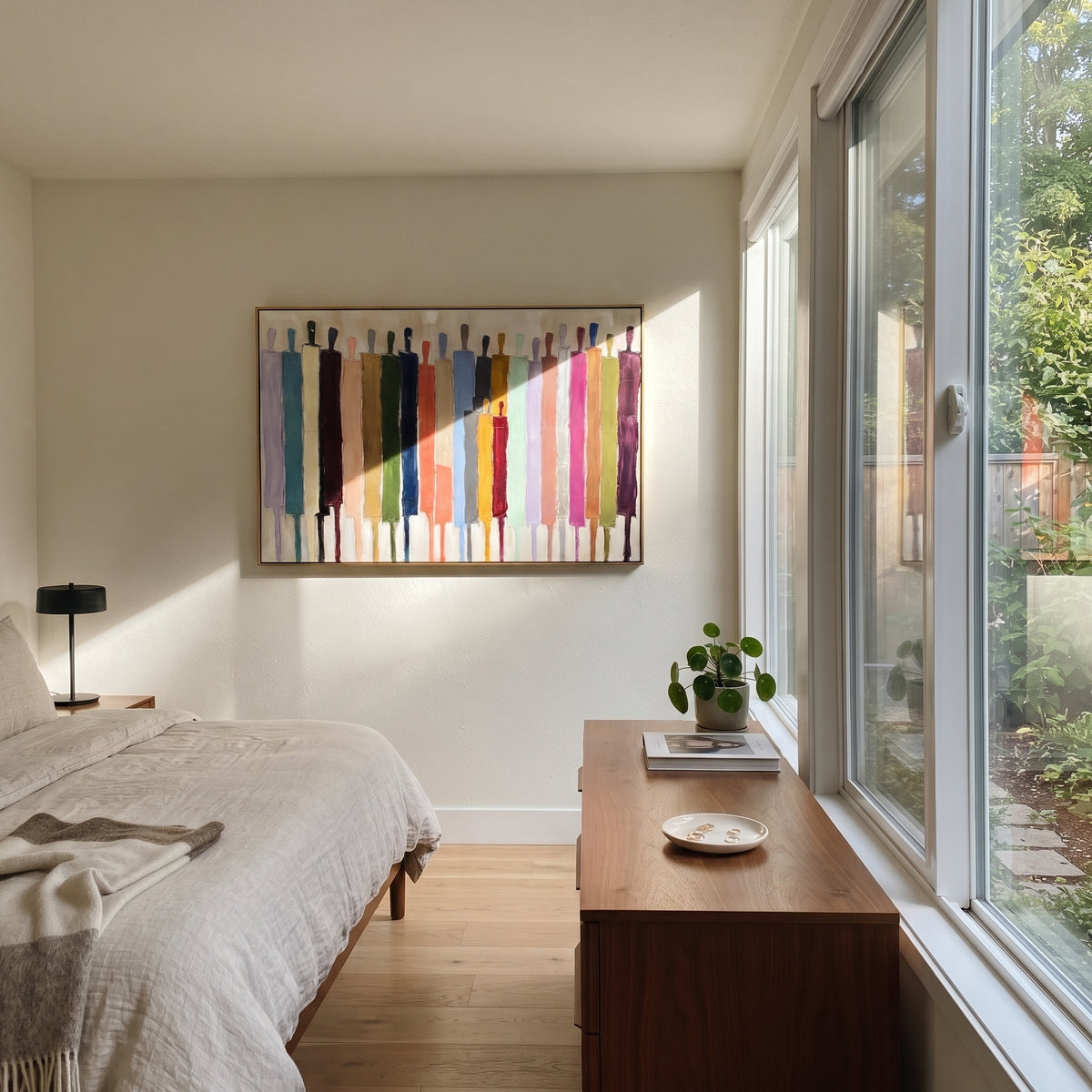 Bright Procession Across White – colorful elongated figures painting, displayed in a bright dining corner